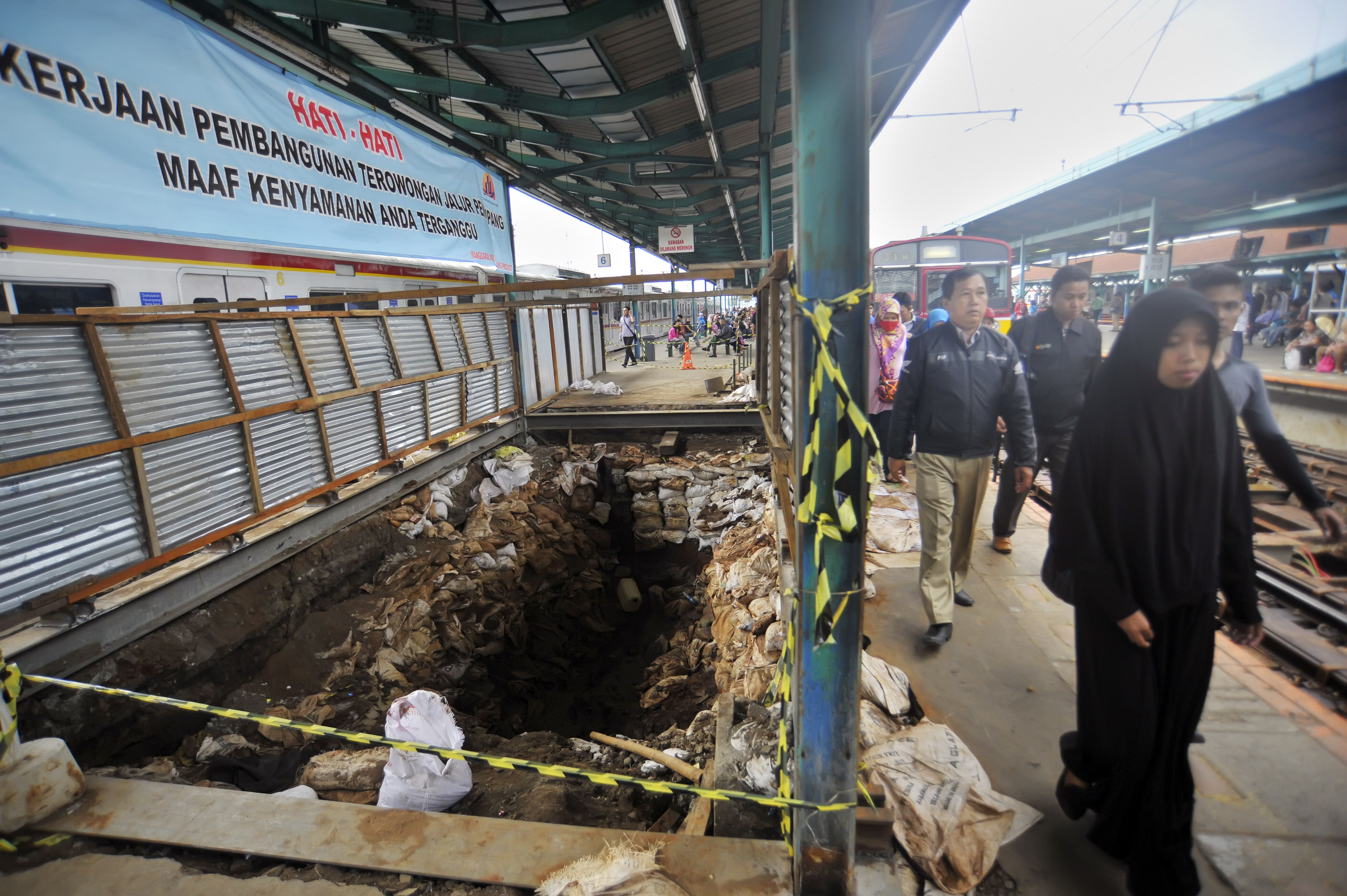 Calon penumpang melintas di samping proyek terowongan pejalan kaki di peron Stasiun Manggarai, Jakarta, Selasa (17/2).