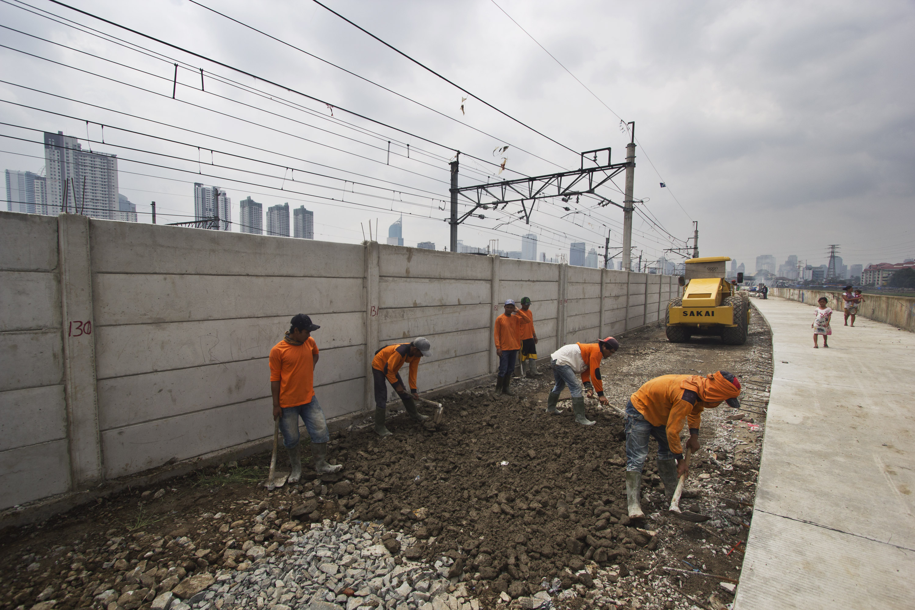 Sejumlah pekerja menyelesaikan proyek pembangunan jalan inspeksi pada sepanjang aliran banjir kanal barat di Jakarta, Selasa (3/3).