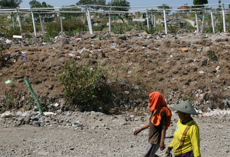 Warga melewati instalasi pipa Gas Metan yang dipasang di atas tumpukan sampah di Tempat Pembuangan Akhir (TPA) Klotok Kota Kediri, Jawa Timur, Kamis (18/6)