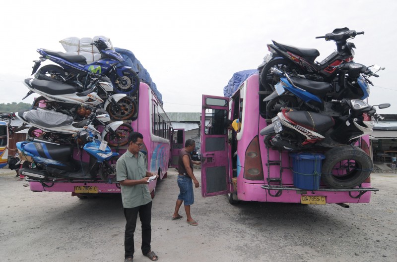 Petugas memeriksa sepeda motor yang diangkut di bagian belakang bus di Terminal Induk Mamboro, Palu, Sulawesi Tengah, Jumat (10/7).