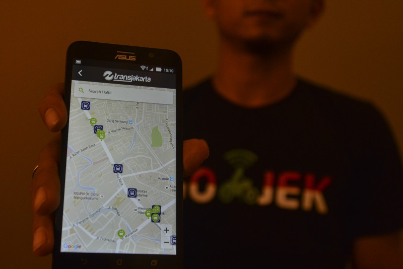 Seorang pria menunjukkan aplikasi transportasi hasil kolaborasi Transjakarta, Qlue, dan Gojek di Balai Kota DKI Jakarta, Rabu (28/10).