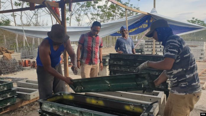 Direktur Yayasan Arsitek Komunitas Indonesia Yuli Kusworo mengamati kegiatan pembongkaran molding atau cetakan panel Beton P1 di bengkel Risha Arkom Palu. (Foto VOA, Yoanes Litha )
