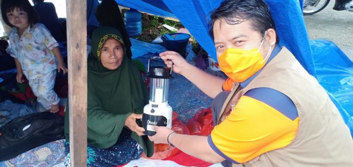Petugas Badan Penanggulangan Bencana Daerah memberikan lampu air garam yang berguna untuk penerangan di lokasi pengungsian bencana