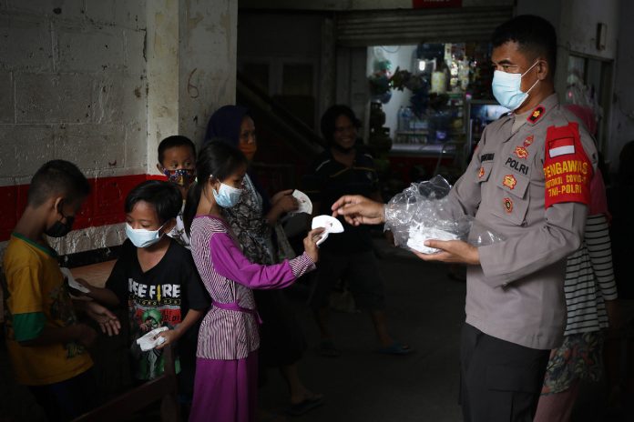 Anggota Polri membagikan masker kepada anak-anak warga Rusun Petamburan, Tanah Abang, Jakarta Pusat, Kamis, 22 Juli 2021