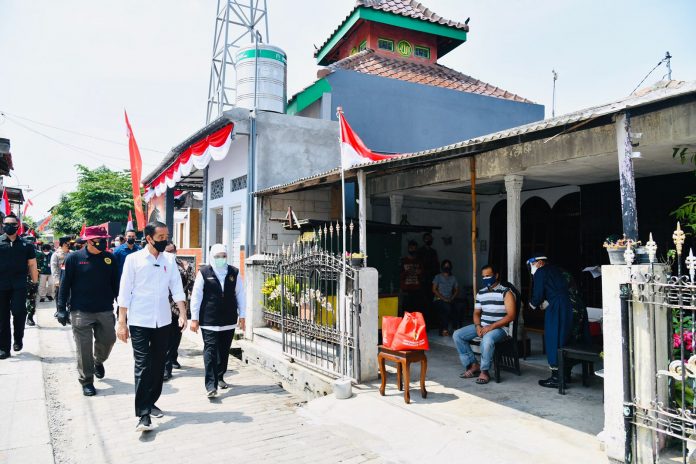 Presiden Joko Widodo meninjau program vaksinasi Covid-19 untuk masyarakat secara pintu ke pintu yang dilaksanakan di Gang Kampung Pesilat, Kecamatan Mejayan, Kabupaten Madiun, Jawa Timur