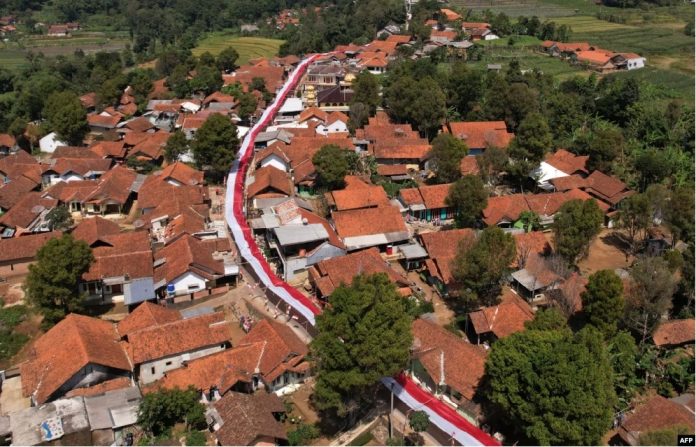 Foto udara menunjukkan kain merah putih sepanjang 1.000 meter digelar di sepanjang jalan di Lemahsugih, Jawa Barat, menjelang perayaan HUT Kemerdekaan RI ke-79. (Foto Timur Matahari AFP)